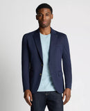 Man wearing a navy blazer over a light blue shirt on a plain background