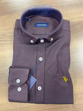 Folded brown dress shirt with collar and buttons on a wooden surface